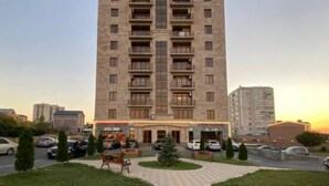 Un grand immeuble à plusieurs étages, doté de balcons et d’une entrée centrale.