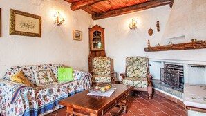 Un salón rústico con techo de madera, un sofá floral, una mesa de madera y una chimenea.