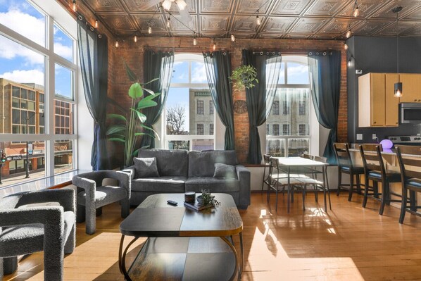 A modern living room with a sofa, chairs, a coffee table, and a dining area with a table and chairs.