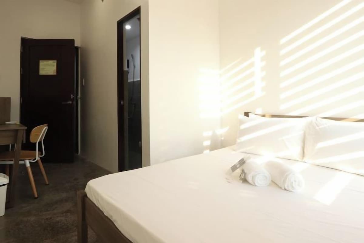 A hotel room with a bed, a desk, and a chair.