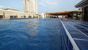 A swimming pool with a tiled edge, surrounded by buildings and a covered walkway. - The Pad Co-Living (Cebu City)