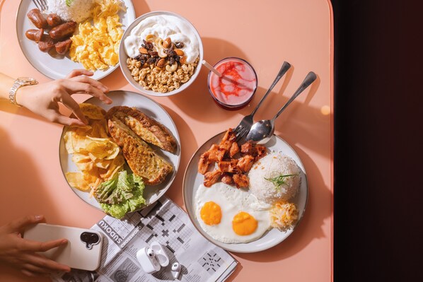 Une table avec différents plats, notamment du riz, des œufs et une boisson.