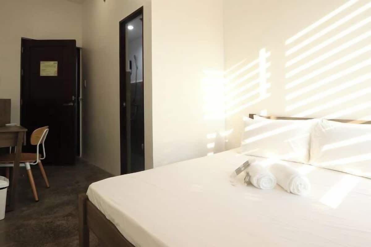 Una habitación de hotel con cama, escritorio y silla.
