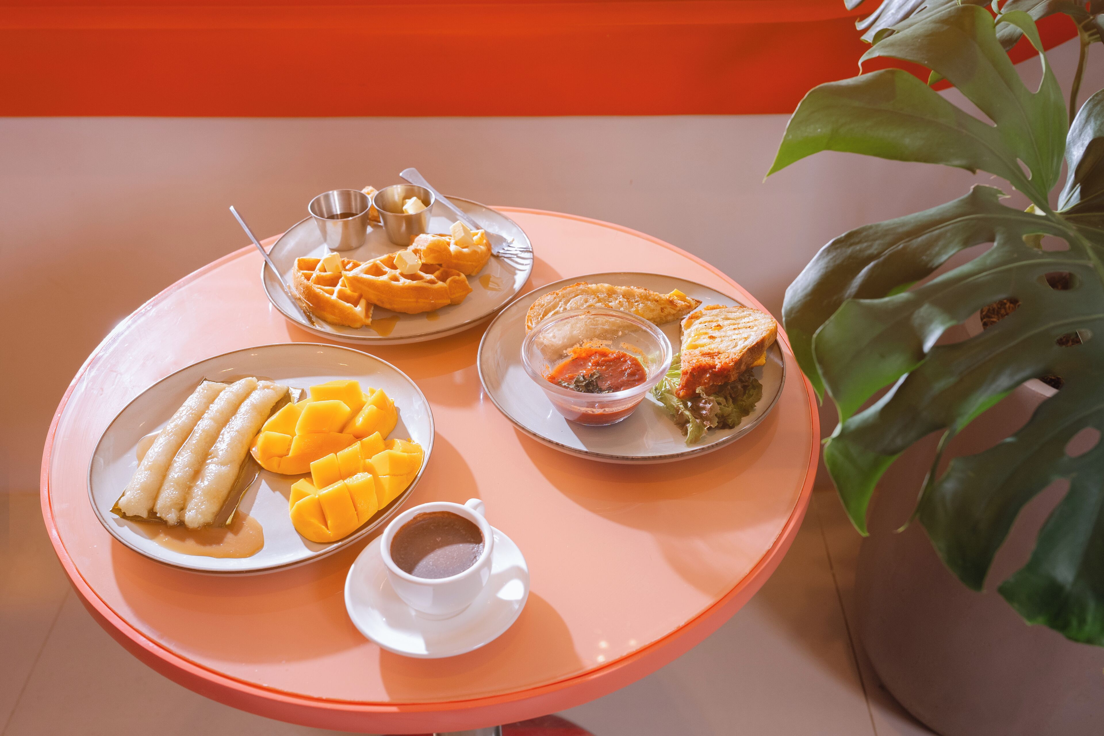 Une table sur laquelle on trouve une variété d’aliments, notamment des gaufres, un sandwich et une tasse de café.