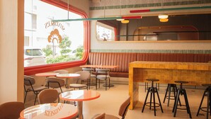 A restaurant interior with booths, round tables, and high stools. - The Pad Co-Living (Cebu City)
