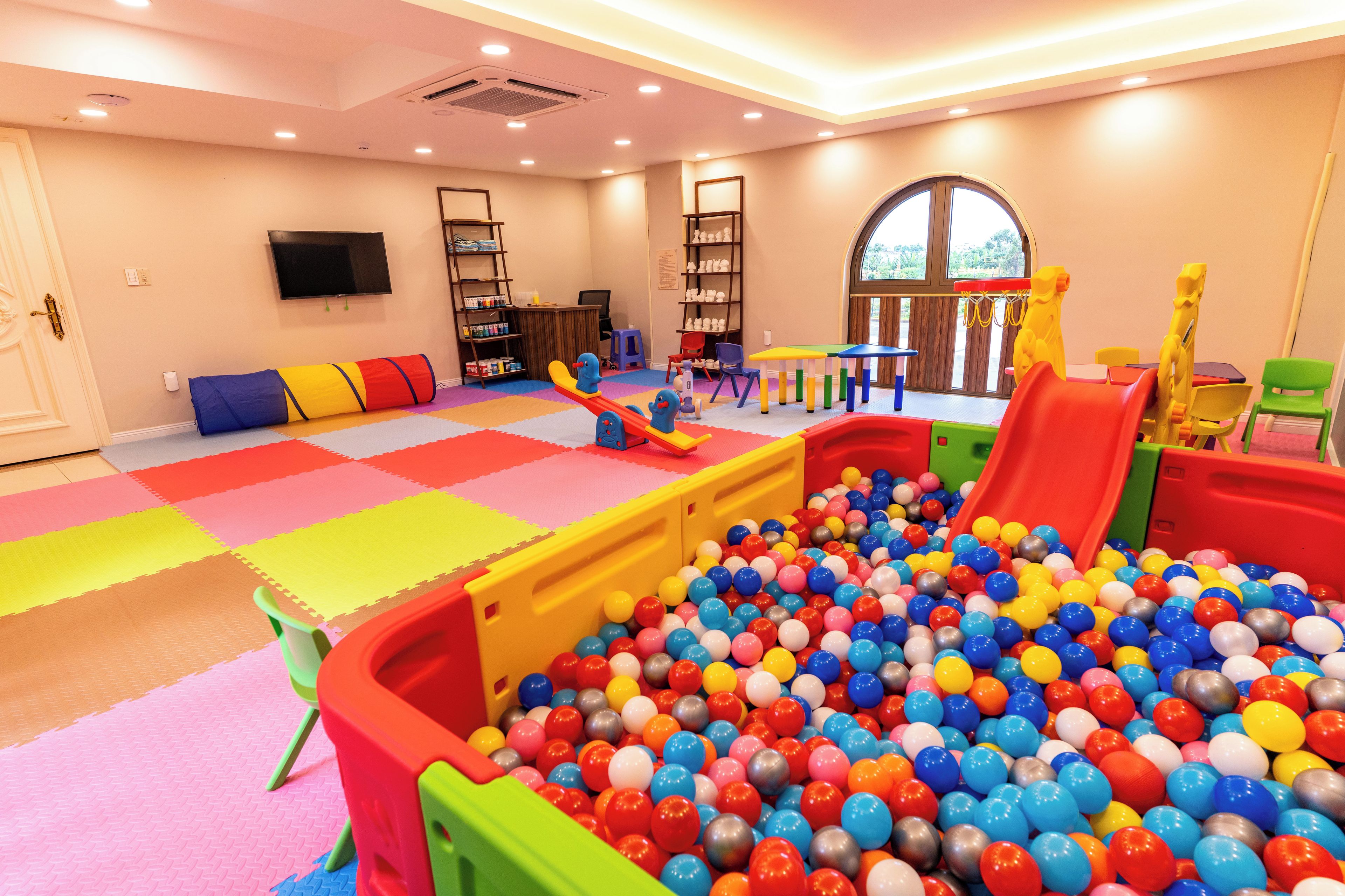 A children's play area with a ball pit, play mats, and various play equipment.