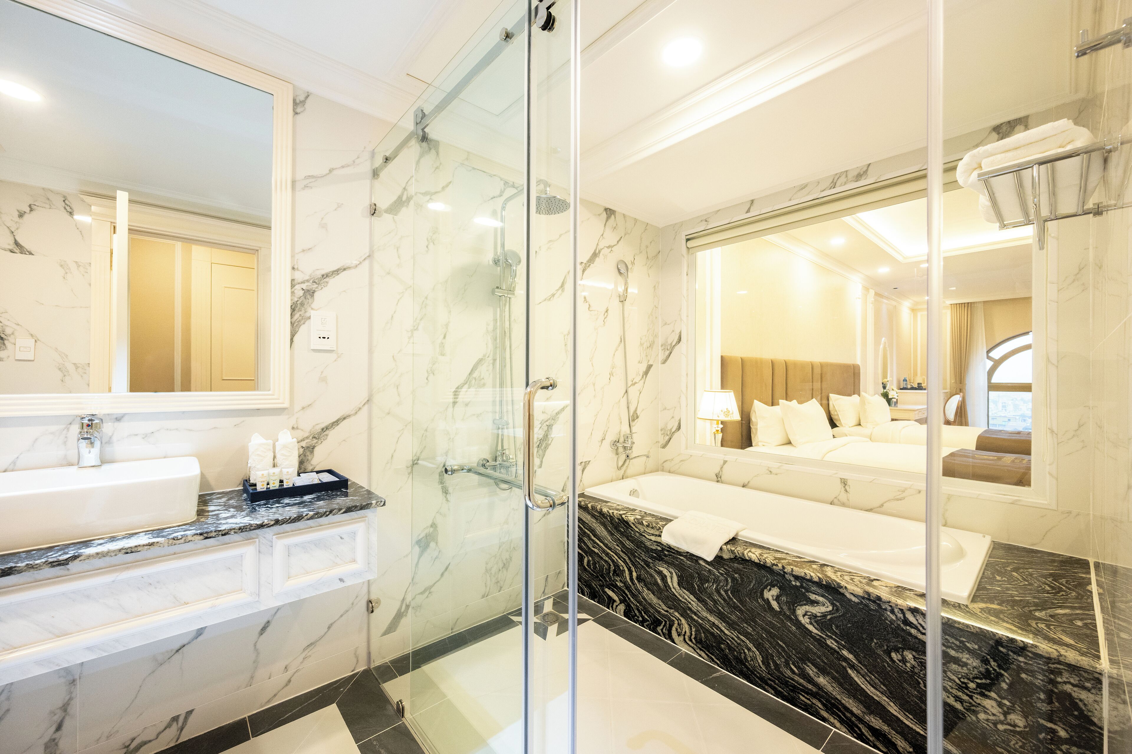A modern bathroom with a glass-enclosed shower, a marble sink, and a large bathtub.