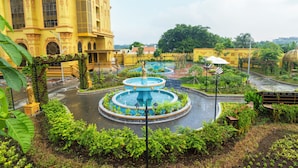 A large yellow building with a fountain in the center surrounded by greenery. - LaChateau (Ho Chi Minh City)