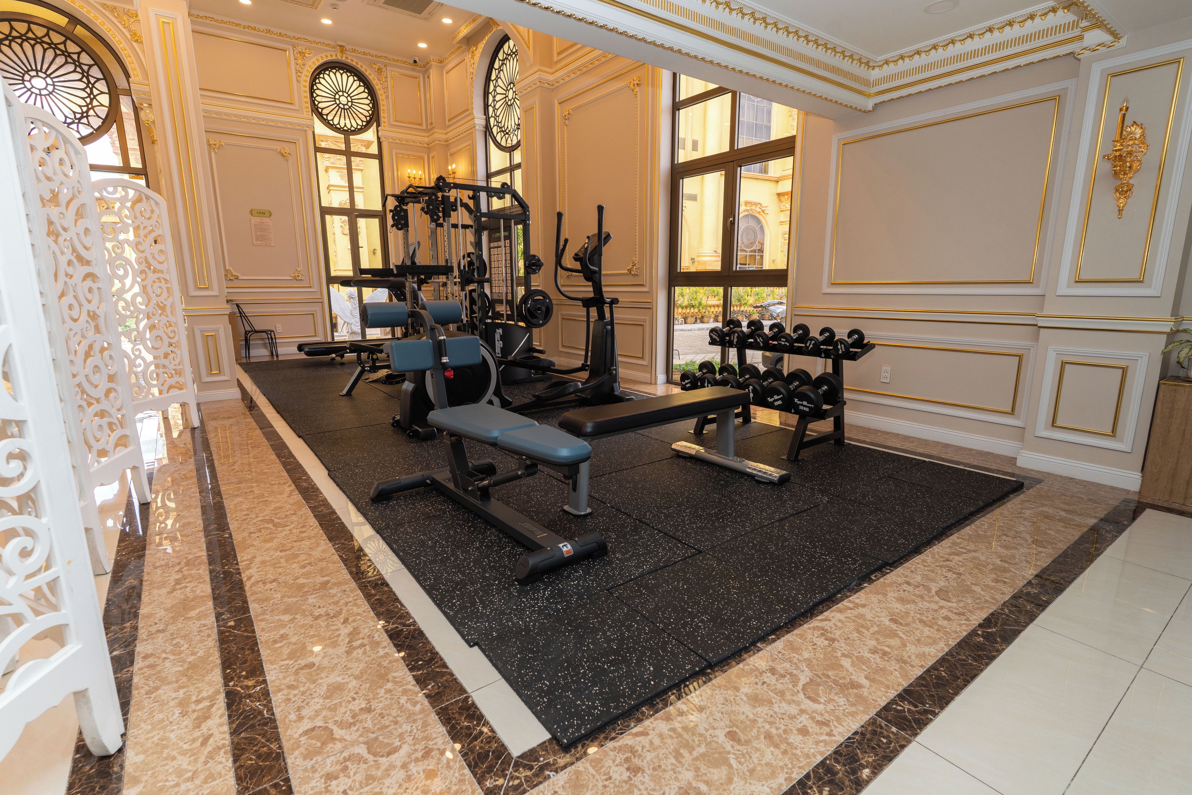 A gym with exercise equipment, a bench, and a rack of dumbbells.