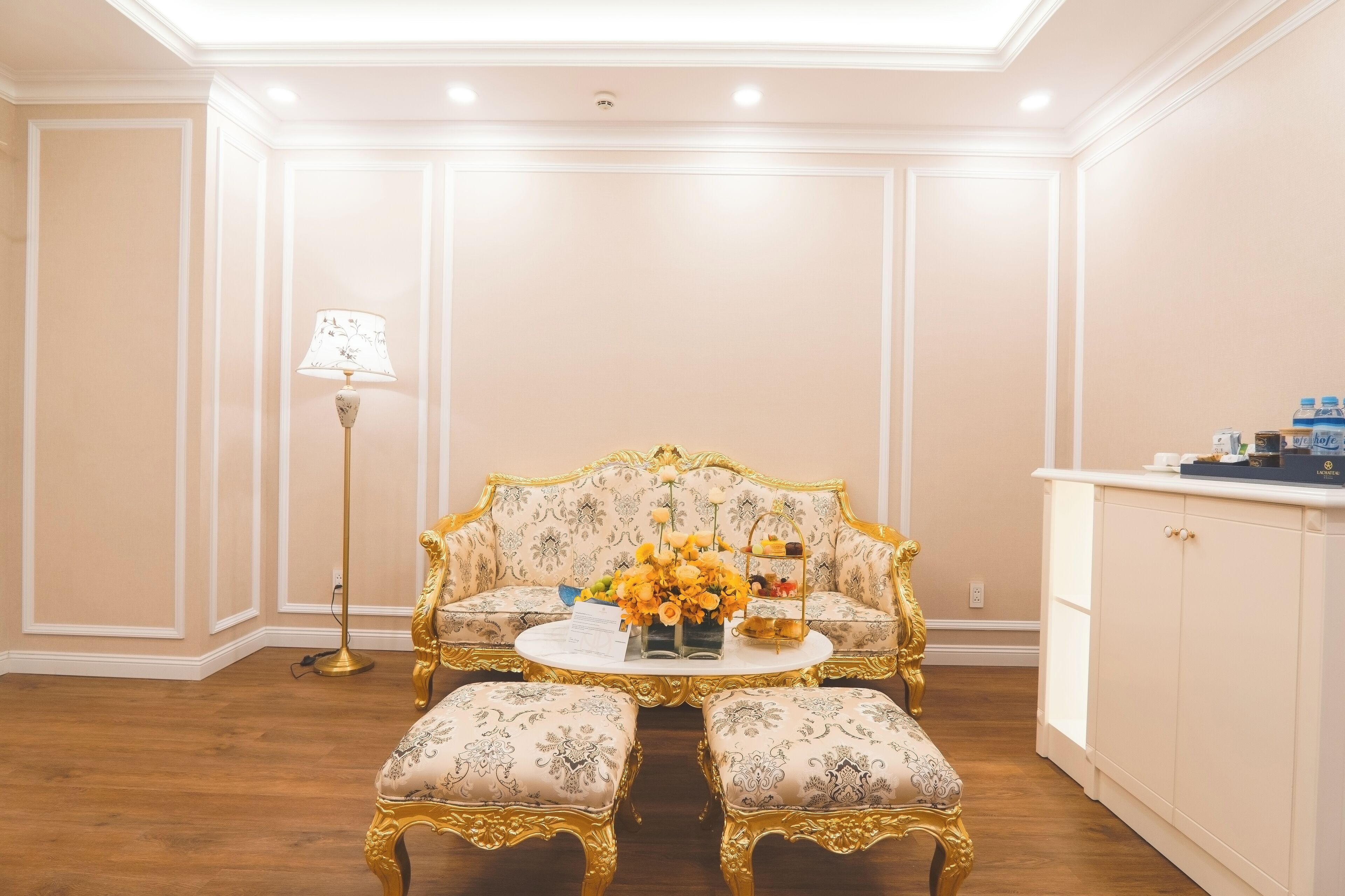 Une pièce comprenant un canapé, une petite table ornée de fleurs, une lampe sur pied et un meuble.