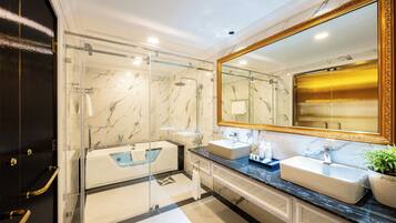 A modern bathroom with a glass-enclosed shower, two sinks, and a large mirror with a gold frame.