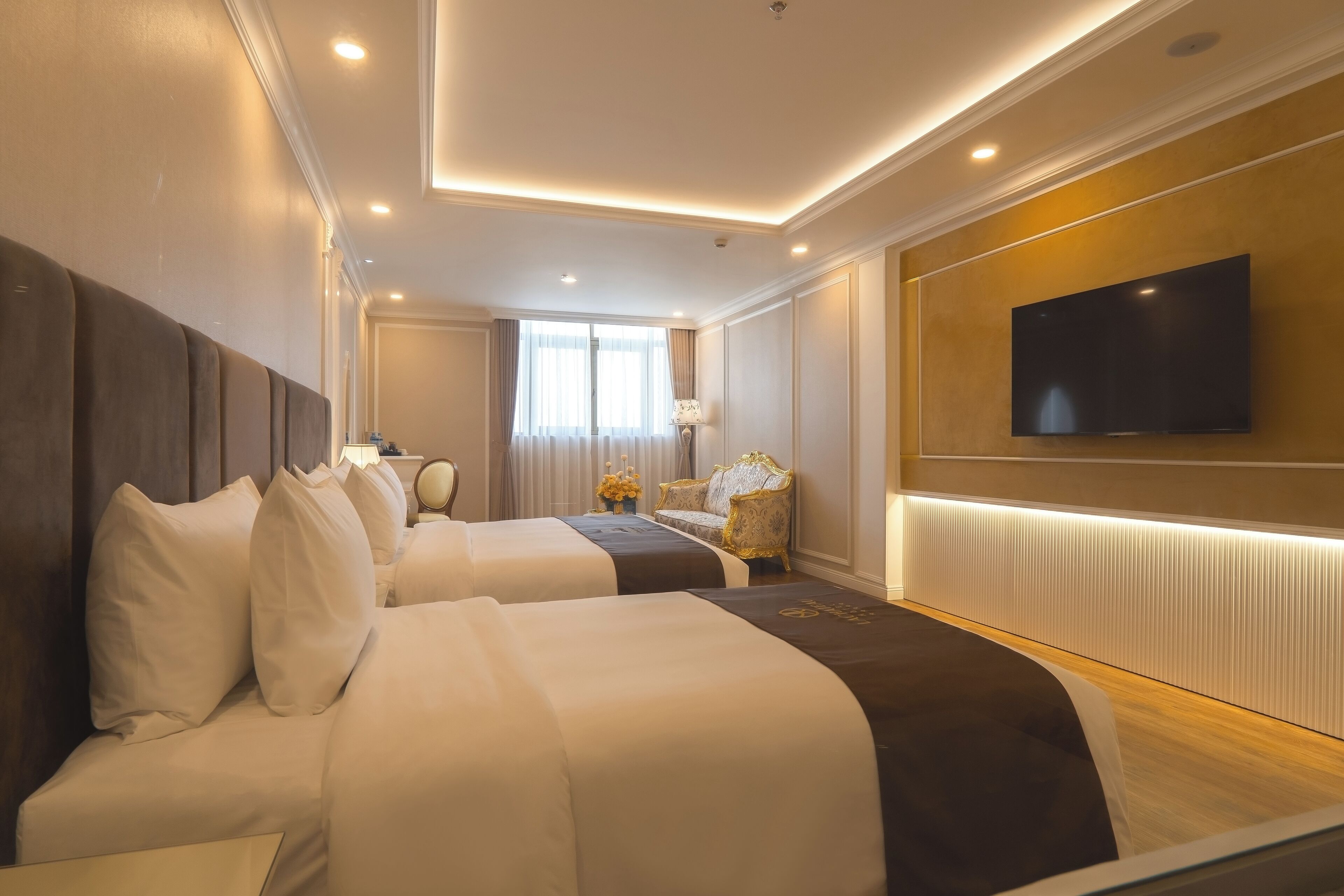 Een hotelkamer met twee bedden, een televisie, een lamp en een raam met gordijnen.