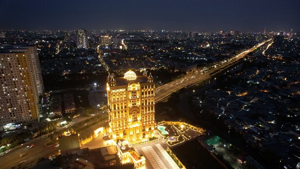 A large, illuminated building with a dome, surrounded by a well-lit plaza and a busy road. - LaChateau (Ho Chi Minh City)