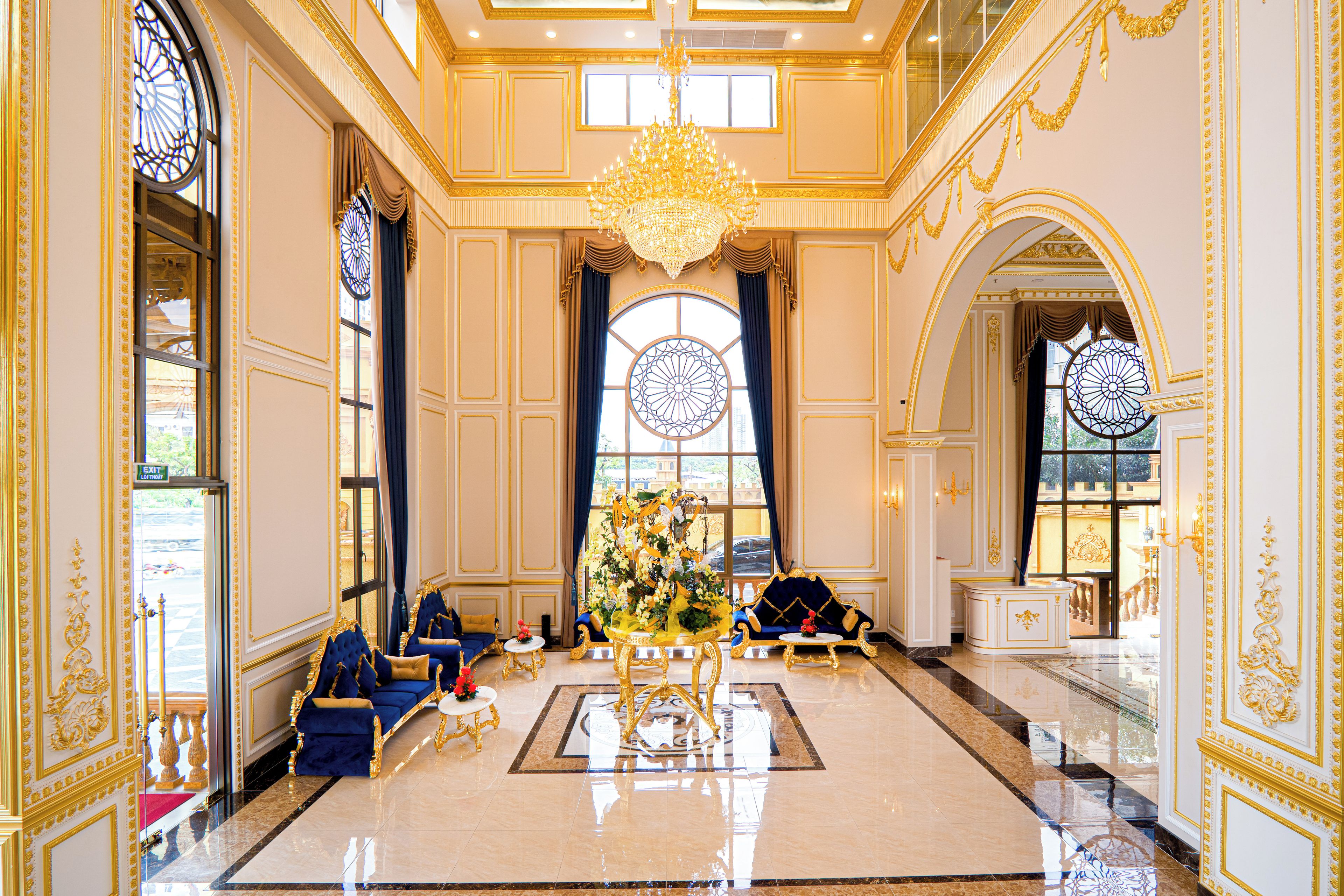 A luxurious lobby with ornate gold detailing, a grand chandelier, and elegant seating arrangements.