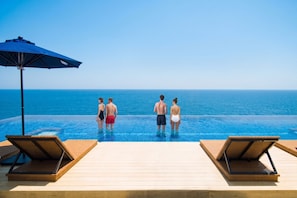 A poolside area with lounge chairs and an umbrella, overlooking a clear blue ocean. - Villa&Glamping Lazy Inn. (Awaji)