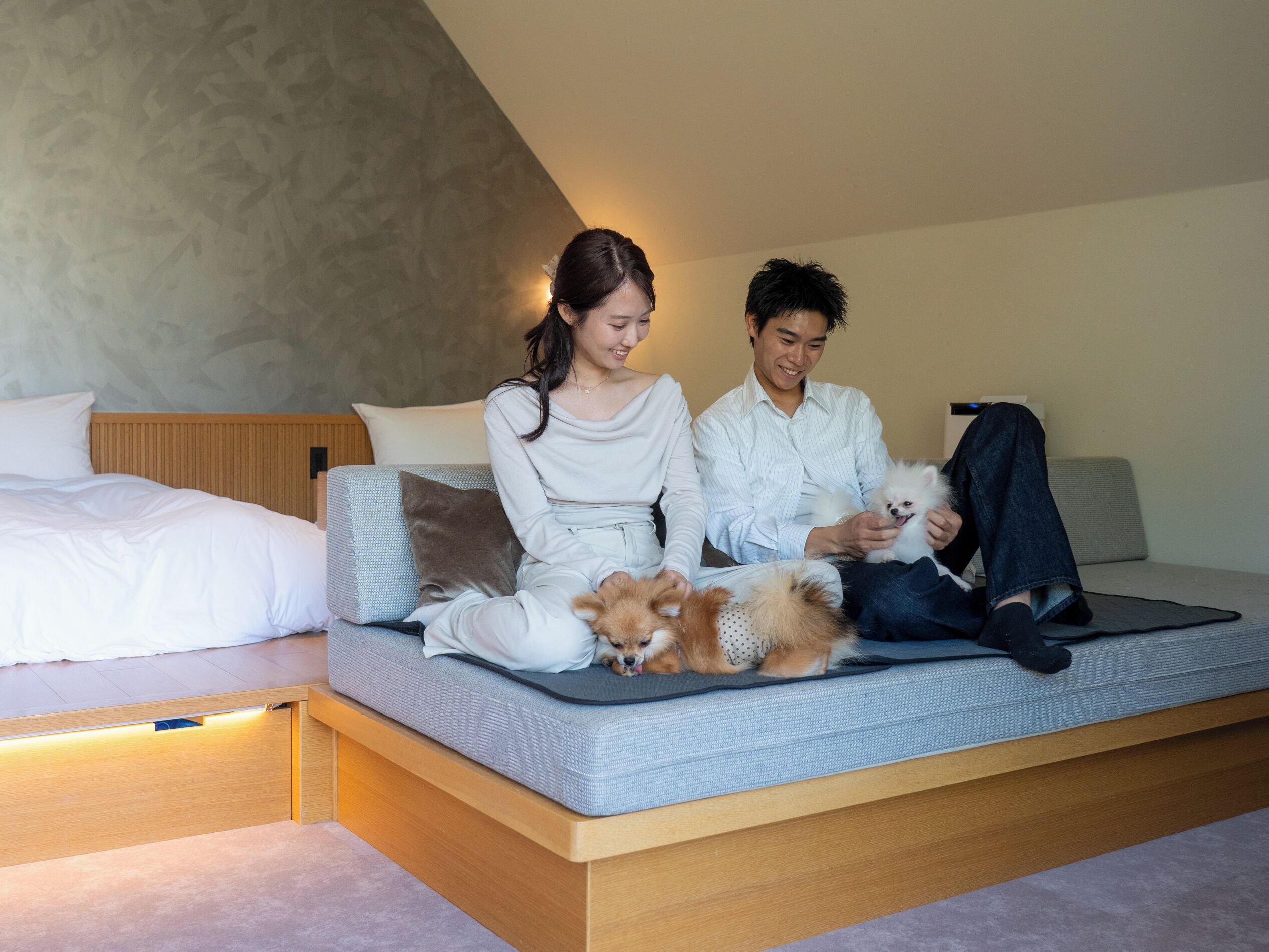 Quarto moderno com cama, sofá e plataforma de madeira.