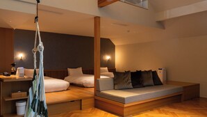 Moderni hotellihuone, jossa on suuri sänky, sohva, riipputuoli ja työpöytä lampun kanssa.