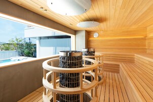 A modern sauna with wooden benches and a circular design, a visible clock, and a view of the outside.