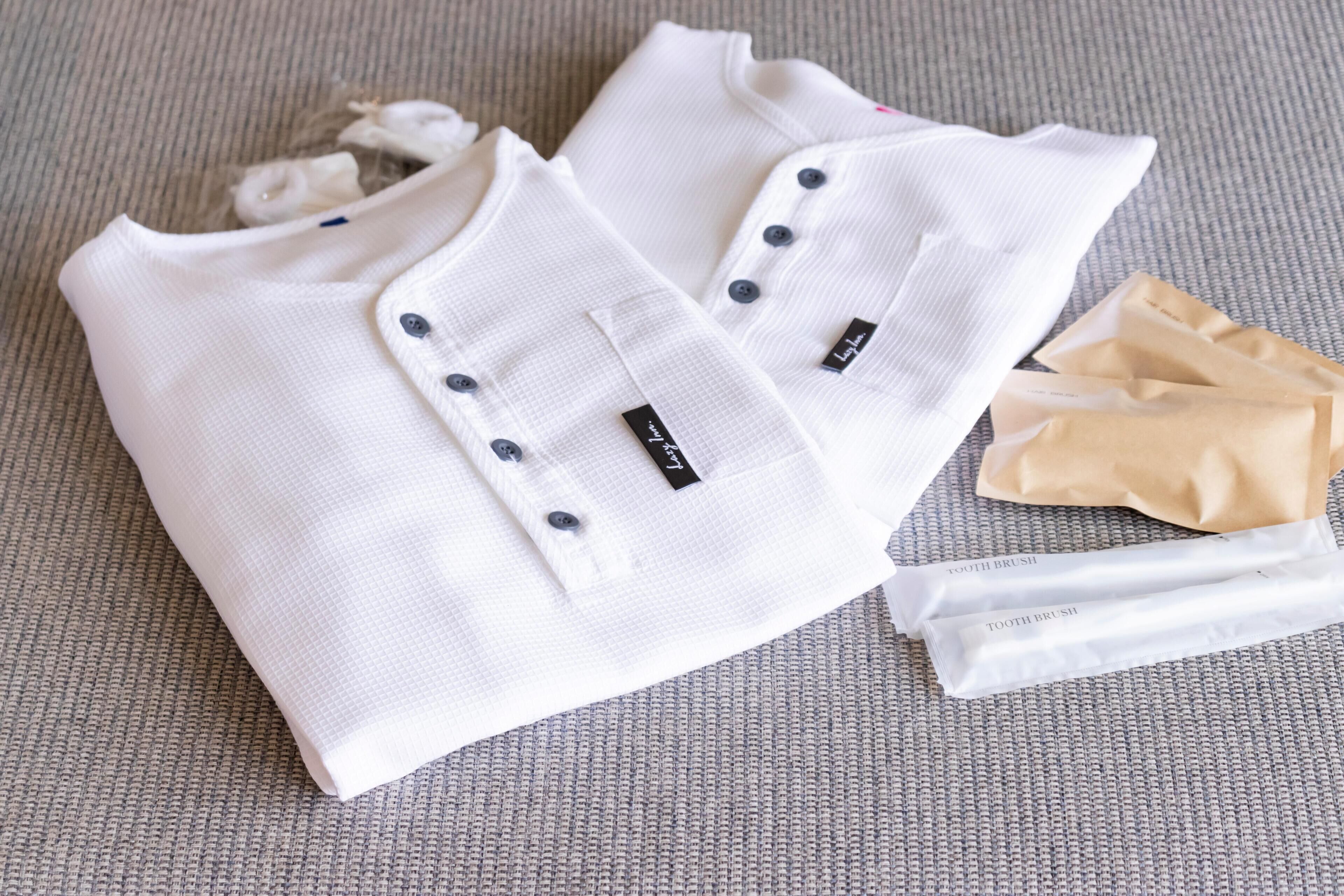 Neatly folded white shirts with buttons and tags, placed on a textured surface.