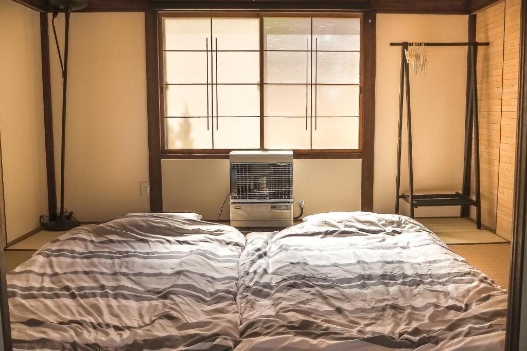 A room with a bed, a window, a heater, and a traditional Japanese sliding door.