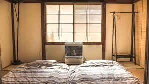 Ein Zimmer mit einem Bett, einem Fenster, einem Heizgerät und einer traditionellen japanischen Schiebetür.