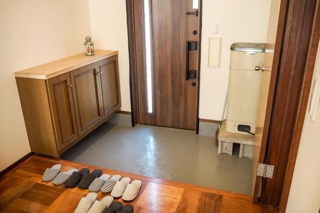 Un couloir avec une armoire en bois, une porte et une poubelle.