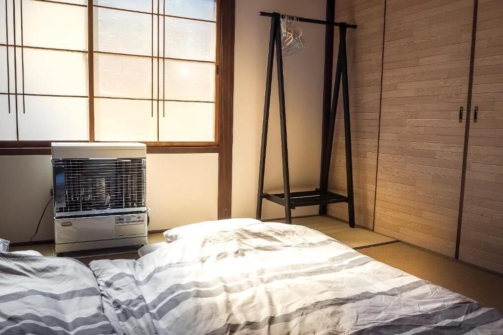 Una habitación con cama, aire acondicionado, armario y ventana con persianas.