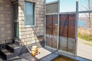 Un baño moderno con pared de piedra, una ventana, un taburete de madera y una pequeña fuente de agua.