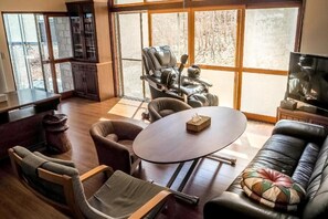A spacious living room with a large window, a massage chair, a round table, and a leather sofa. - TOYA ONSEN VILLA (Usu-gun, Sobetsu-cho, Sobetsu ONSEN)