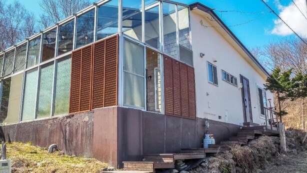 Ein modernes Haus mit großen Fenstern, einer Holztür und einer kleinen Veranda.