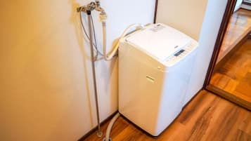 Un chauffe-eau doté d’un panneau de commande, raccordé à un robinet fixé au mur et à un tuyau flexible.