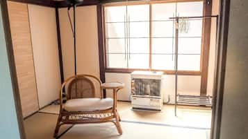 Una habitación japonesa tradicional con suelo de tatami, una silla de bambú, una pequeña mesa y un calentador.