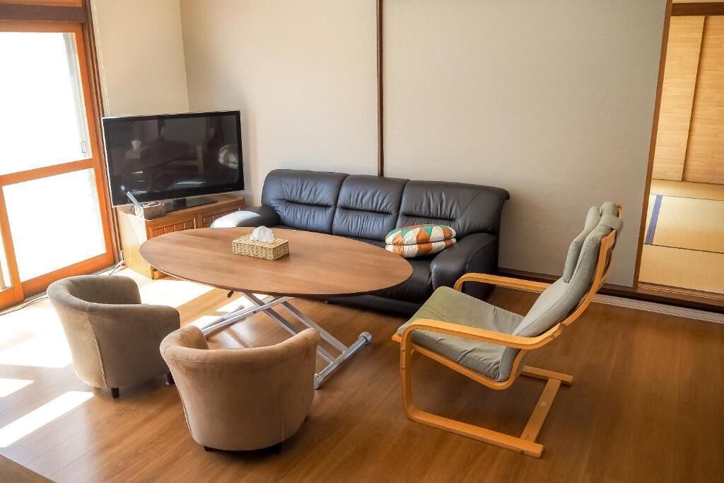Una sala moderna con un sofá de cuero, una mesa de centro de madera y dos sillones.