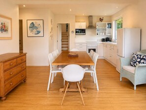 A modern kitchen with white cabinets, a wooden dining table, and white chairs.