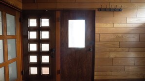 A wooden door with frosted glass panels and a light fixture above it. - Gray house toya (Toyako)