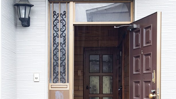 A wooden door with a glass panel, a metal decorative panel, and a small step leading to the entrance. - Gray house toya (Toyako)