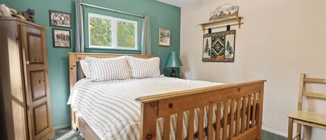 Une chambre à coucher avec un lit en bois, une fenêtre, une armoire et une chaise.