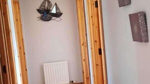 Une pièce avec des portes en bois, un radiateur blanc et un luminaire fixé au mur.