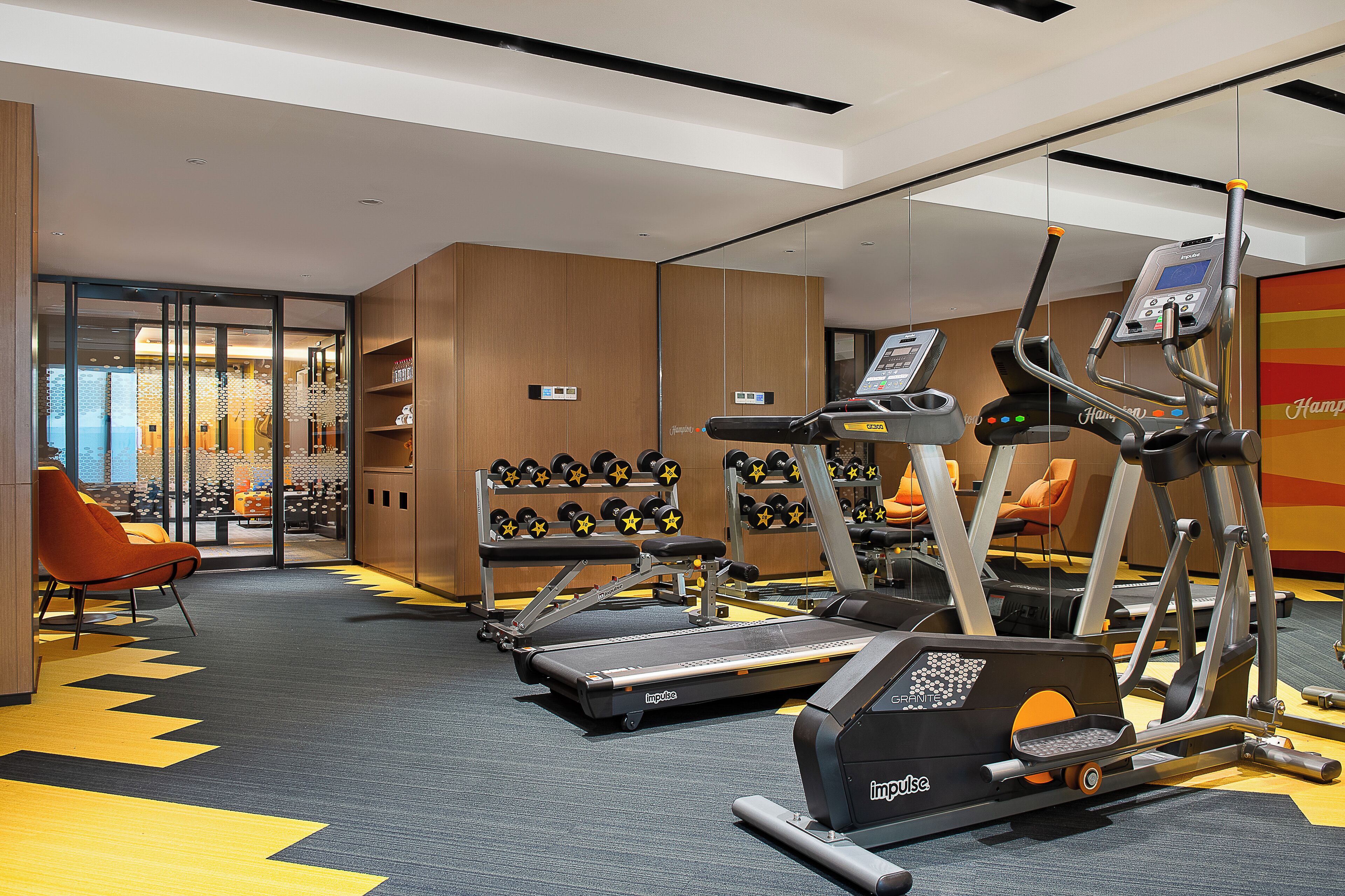Un gimnasio con cintas de correr, elípticas y mancuernas.