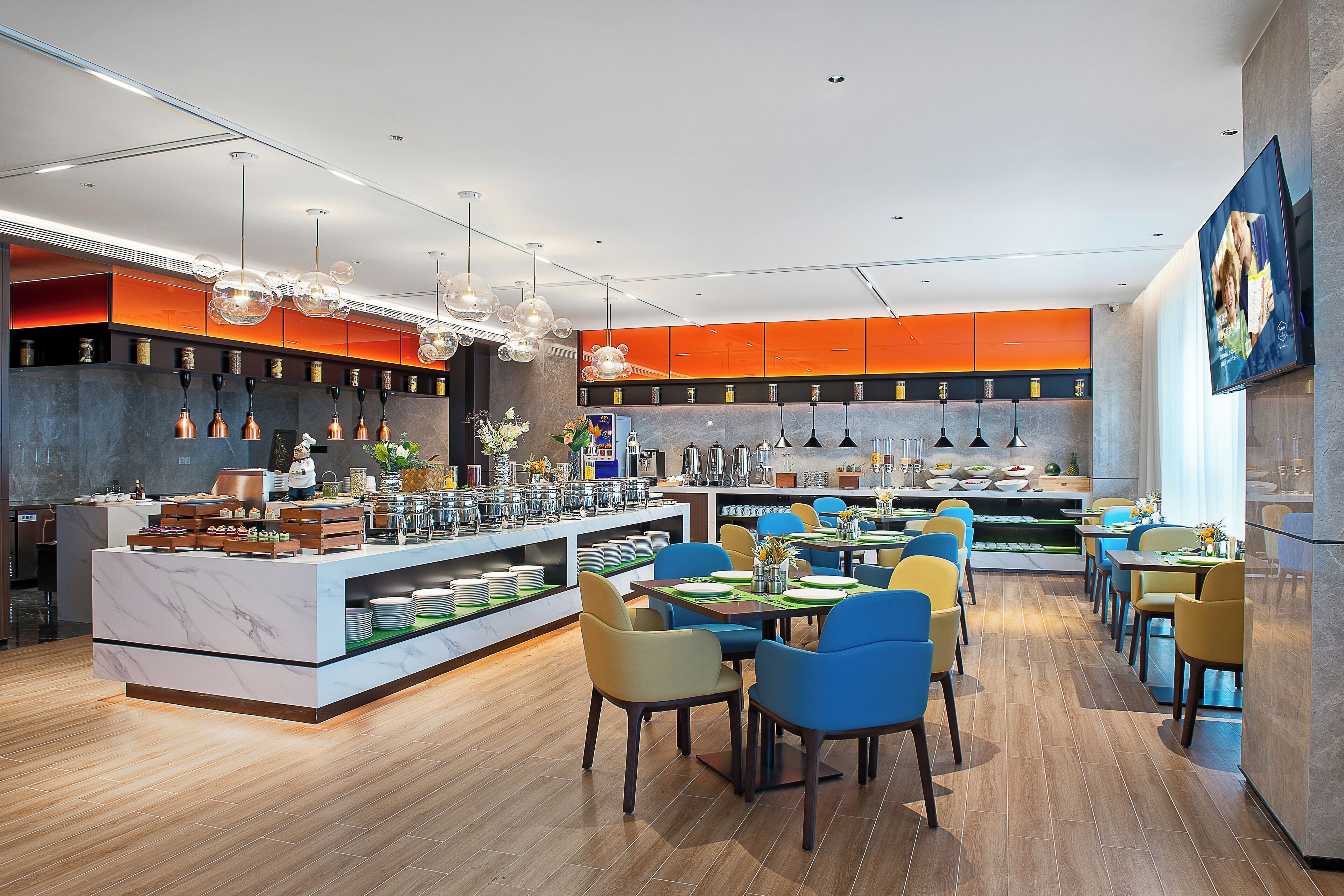 Un restaurante moderno con barra de mármol, sillas de colores y diversas opciones para comer.