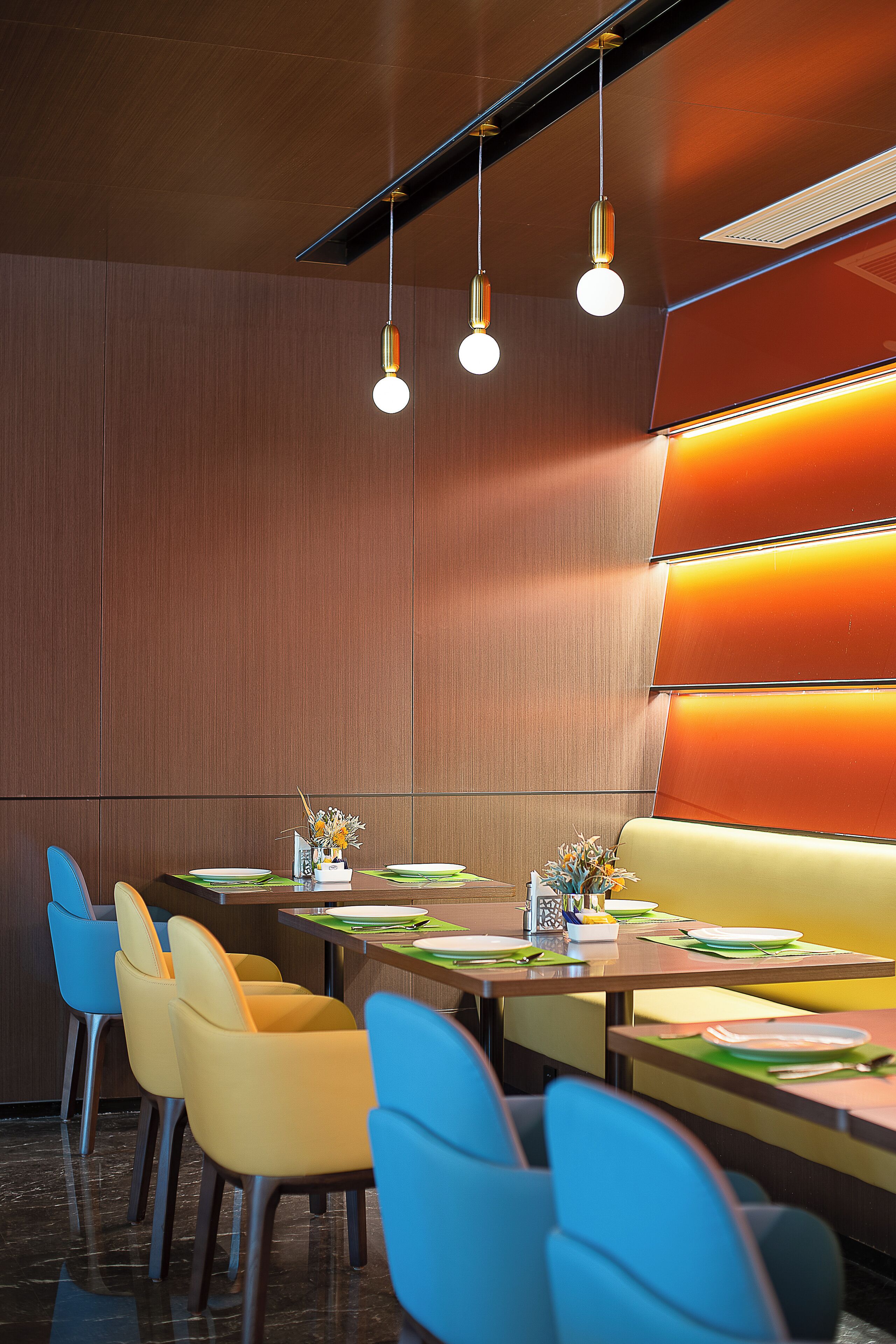 A modern dining area with a long table, multiple chairs, and overhead lighting.
