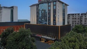 Un hotel moderno con un letrero llamativo, grandes ventanales y techo plano.