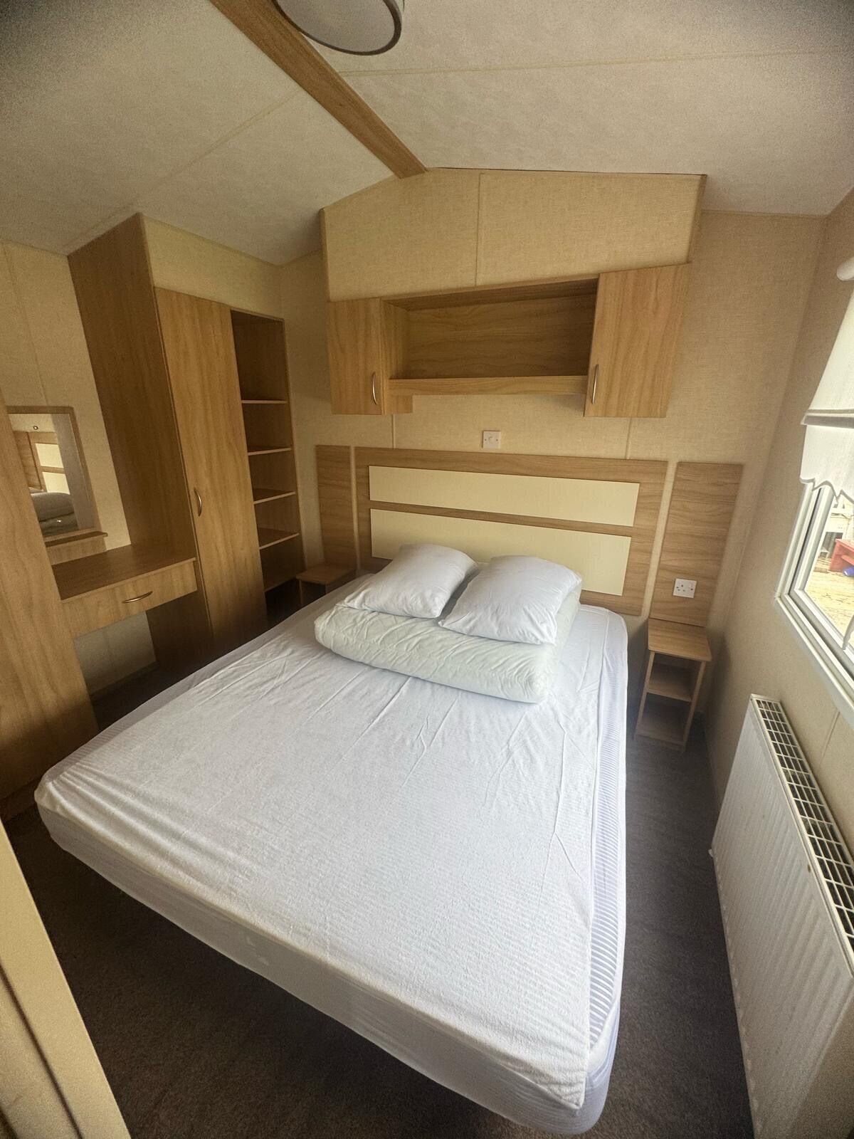 Un dormitorio pequeño con cama, estanterías integradas y una ventana.