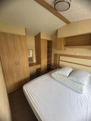 Een slaapkamer met een bed, een houten garderobe en ingebouwde planken.