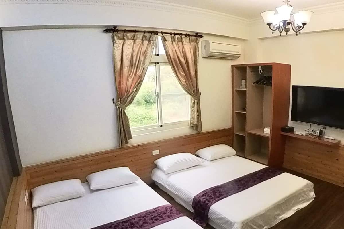 A hotel room with two beds, a TV, a wardrobe, and a window with curtains.