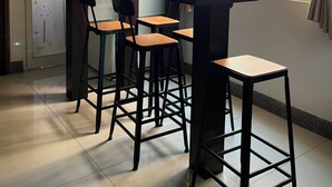 A modern kitchen with a bar area, featuring a glass countertop, bar stools, and a hanging pendant light. - Feng Ming home stay (Jinning)