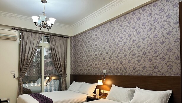 A hotel room with two beds, a chandelier, a window with curtains, and a patterned wallpaper. - Feng Ming home stay (Jinning)