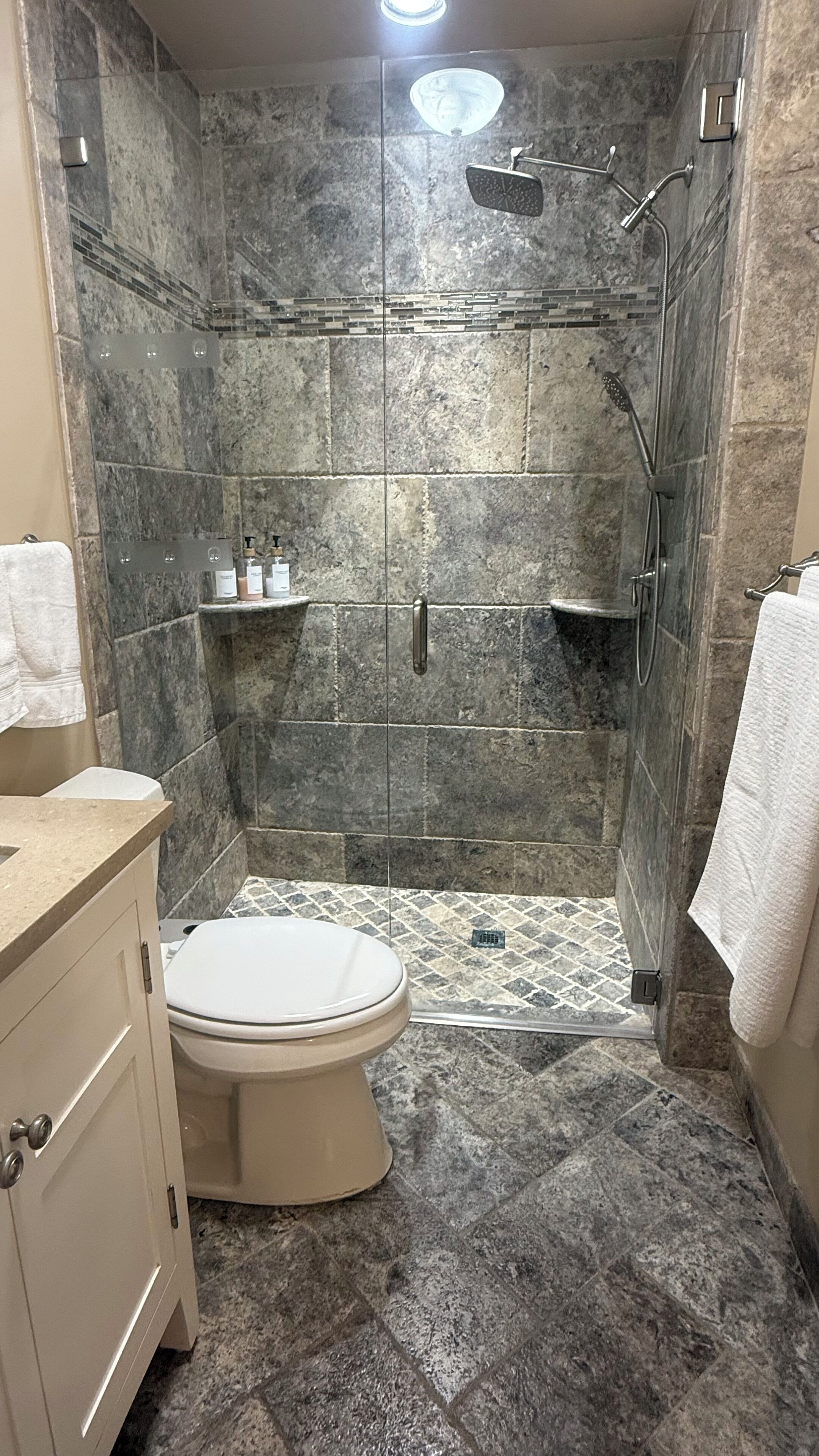 A bathroom with a shower, toilet, and vanity.