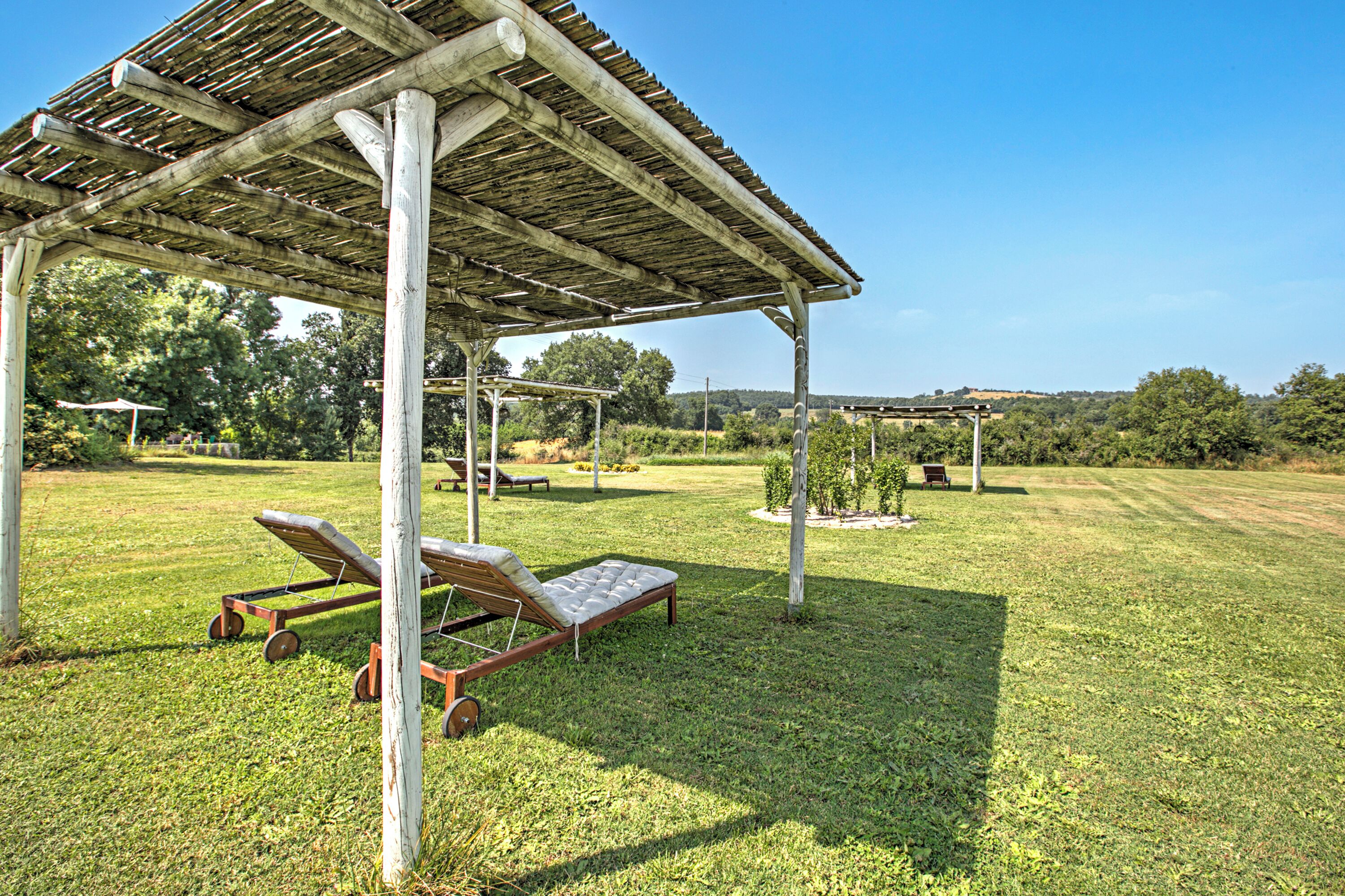 Ein überdachter Außenbereich mit zwei Holzliegen und einer Pergola.