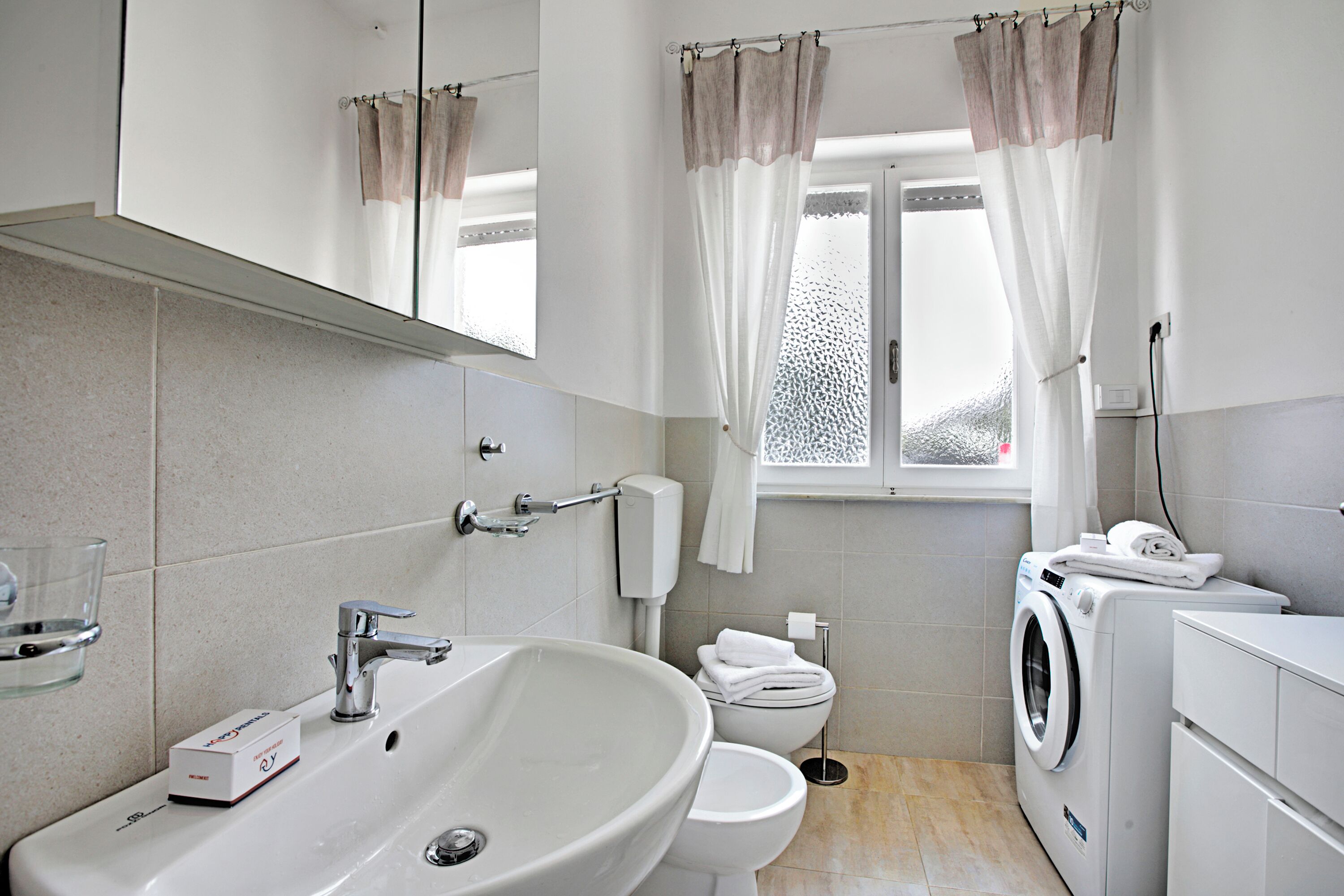 A modern bathroom with a large sink, toilet, and washing machine.